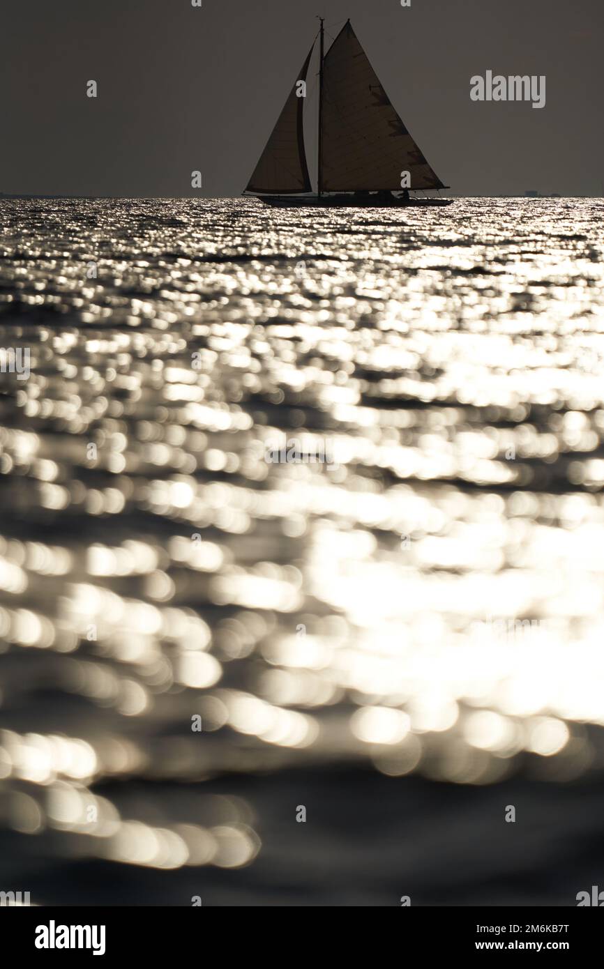 Yacht classique en mer au coucher du soleil, ciel clair, reflet du soleil sur l'eau Banque D'Images