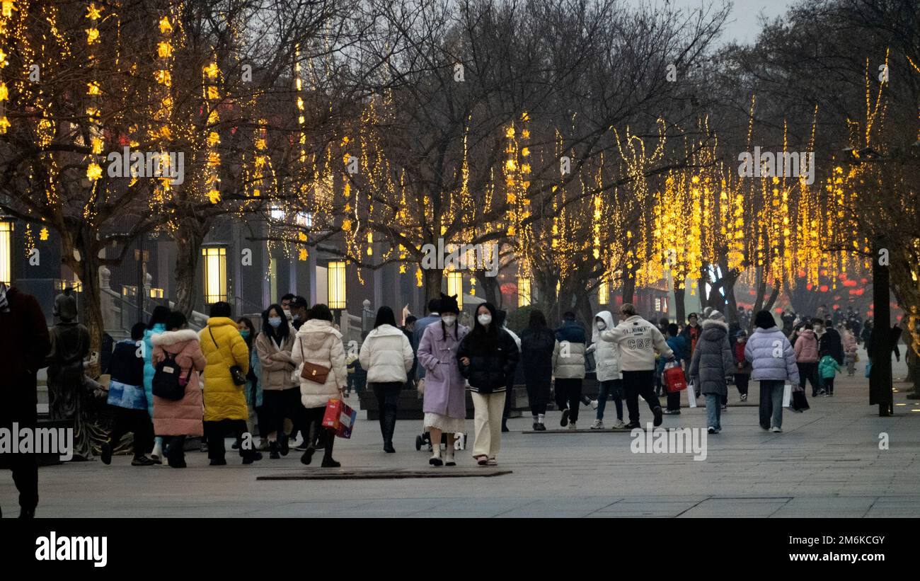XI'AN, CHINE - 4 JANVIER 2023 - des copybooks lumineux sont vus sur les arbres tandis que les touristes se promèdent le long d'une rue piétonne à la grande Pagode Wild Goose pittoresque sp Banque D'Images