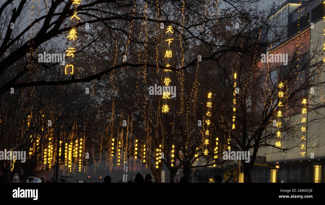 XI'AN, CHINE - 4 JANVIER 2023 - des copybooks lumineux sont vus sur les arbres tandis que les touristes se promèdent le long d'une rue piétonne à la grande Pagode Wild Goose pittoresque sp Banque D'Images