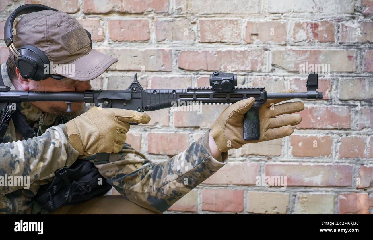 Cycle de formation en service pour les troupes de police civile. Homme avec un fusil debout sur le côté près du mur de brique pendant les armes à feu avancées, defe Banque D'Images