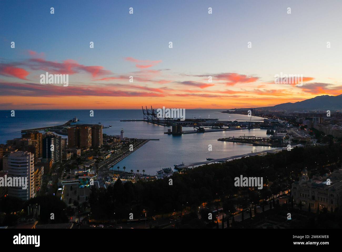 Vue aérienne avec silhouette de grues industrielles au coucher du soleil dans le port de Malaga, Andalousie, Espagne. Banque D'Images