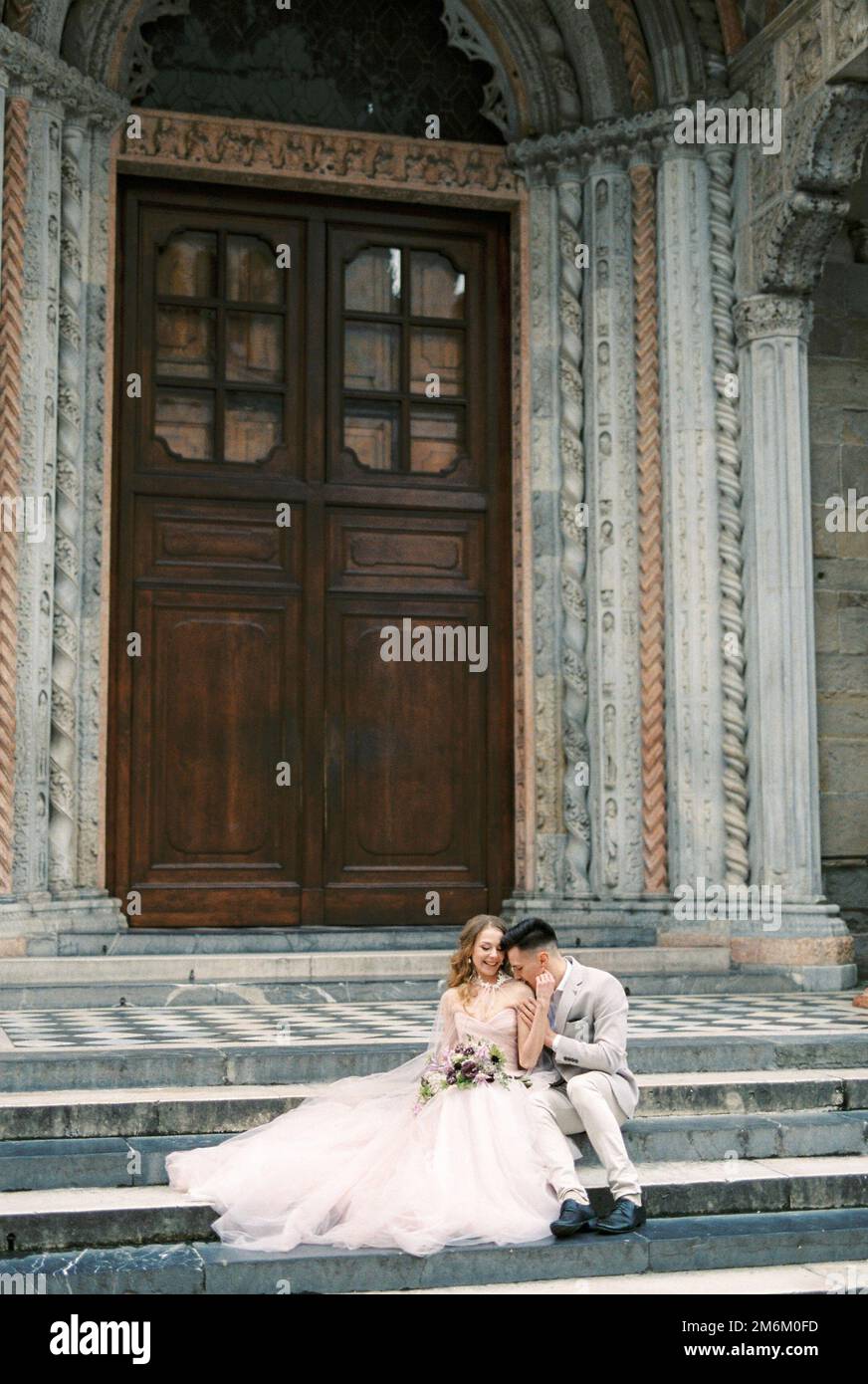 La mariée et le marié s'assoient sur les marches de l'église de Santa Maria Maggiore. Bergame, Italie Banque D'Images