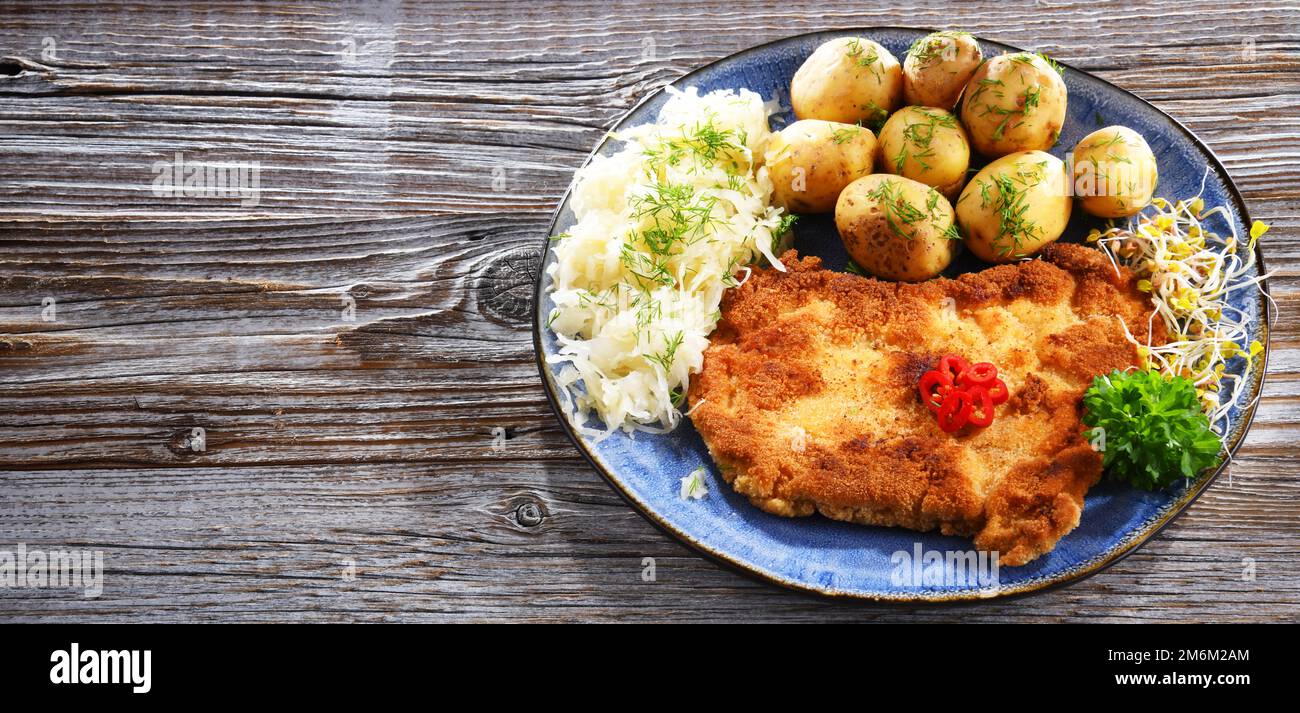 Côtelettes panées de porc enrobées de chapelure servie avec des pommes de terre et du chou Banque D'Images
