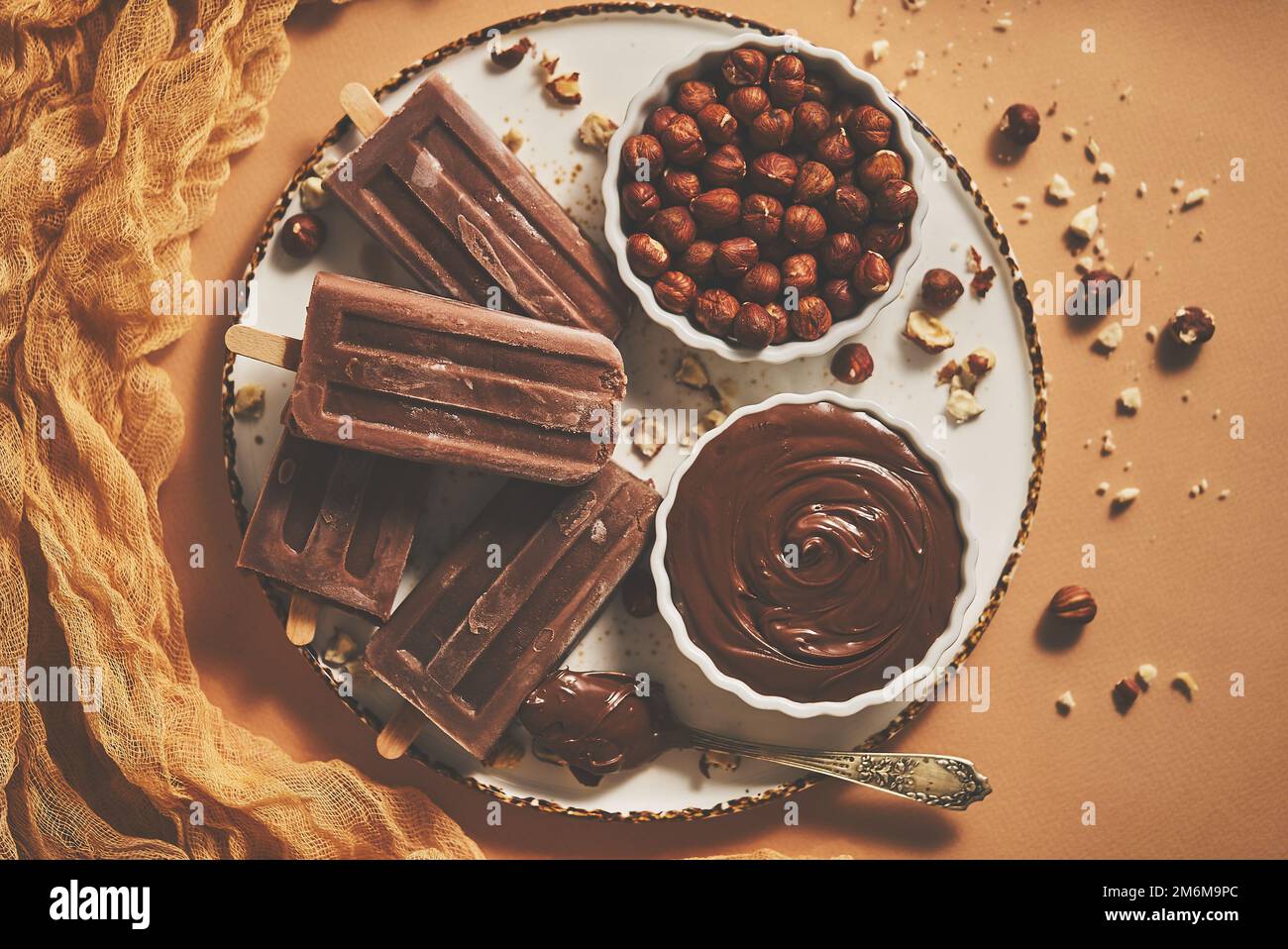 Des pop-glaces au chocolat et aux noisettes servies avec du chocolat fondu sur une assiette blanche Banque D'Images