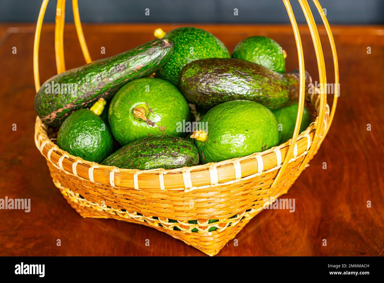 Pile de différentes variétés d'avocat vert frais dans un panier en bambou en osier. Banque D'Images