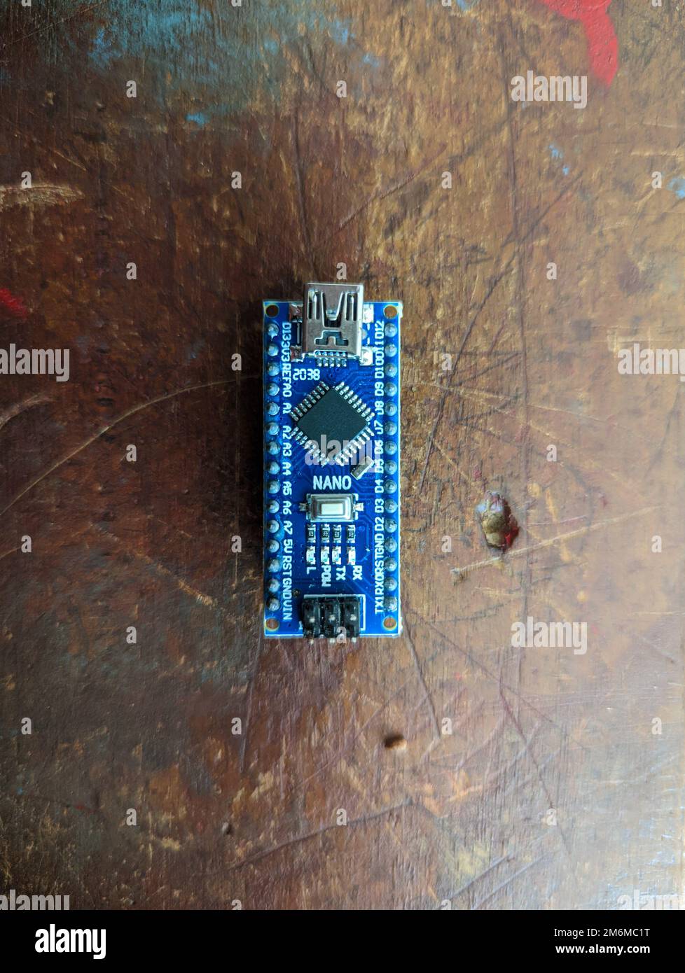 Carte de micro-contrôleur Arduino nano utilisée pour les applications robotiques, informatiques et d'automatisation isolées sur une table en bois en gros plan Banque D'Images
