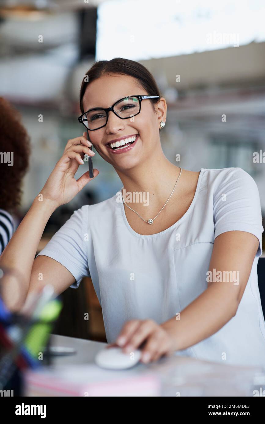 Je suis heureux de pouvoir vous aider. une jeune femme d'affaires assise à son bureau parlant au téléphone. Banque D'Images