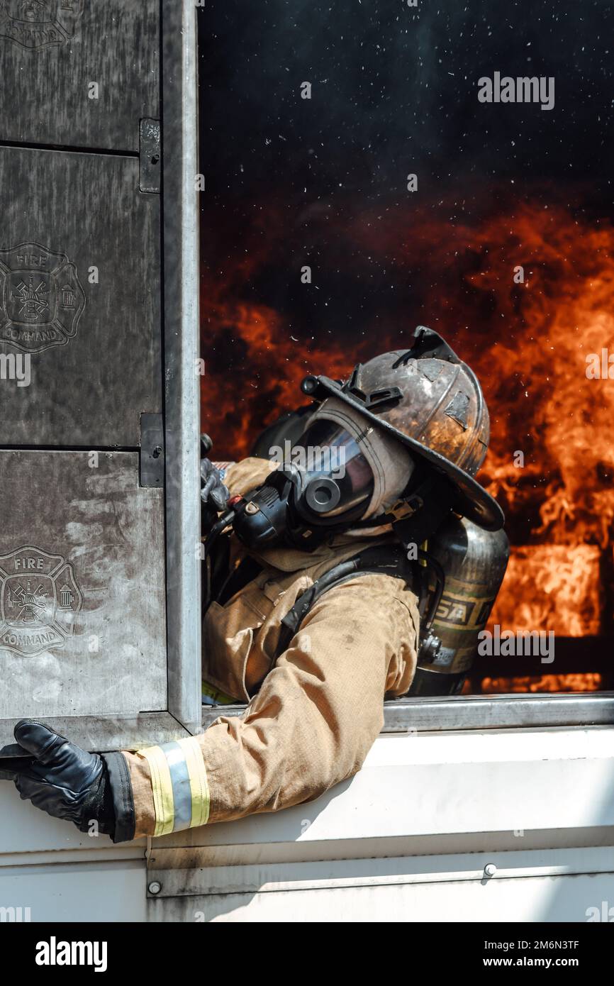 Un pompier de l'escadron du génie civil 316th ferme une fenêtre lors d'un incendie simulé dans un bâtiment tout en participant à l'entraînement interagences de lutte contre l'incendie de l'inan à la base interarmées Andrews, Maryland, 2 mai 2022. L'équipe a suivi une formation sur brûlage en direct pour mettre en pratique les techniques et les procédures de lutte contre les incendies dans un environnement réaliste, en s'assurant qu'elles sont prêtes à atténuer les dommages et à sauver des vies. Banque D'Images