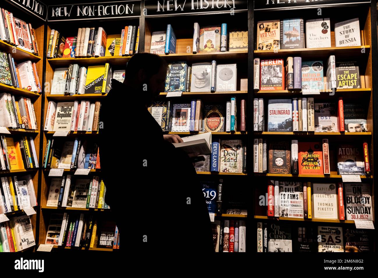 La silhouette d'une personne qui navigue parmi les livres dans une boutique de livres Waterstones en Angleterre au Royaume-Uni. Banque D'Images