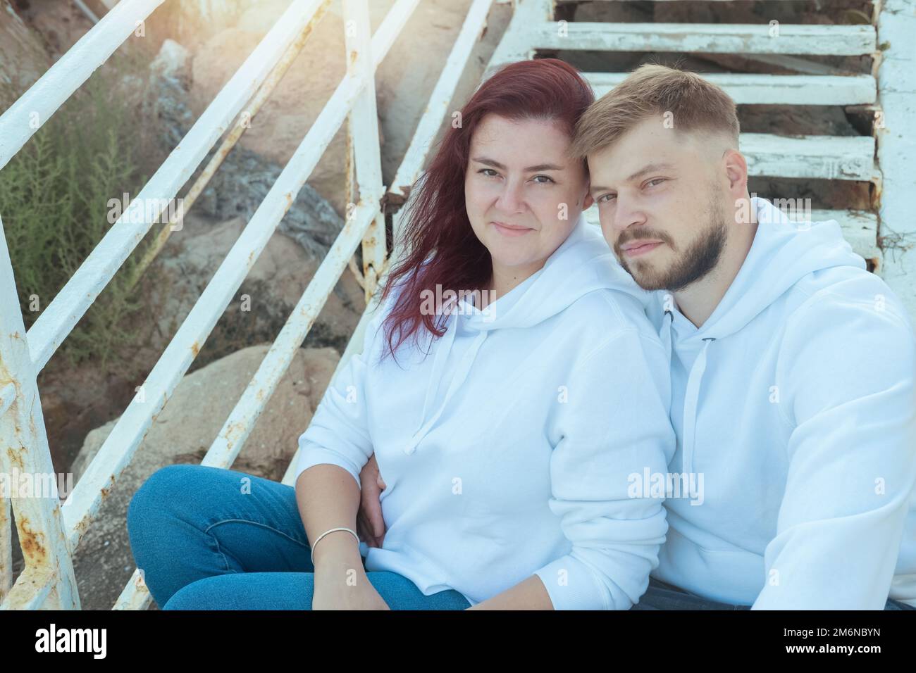 Jeune beau couple mixte de course est assis sur les escaliers et embrassant. Banque D'Images