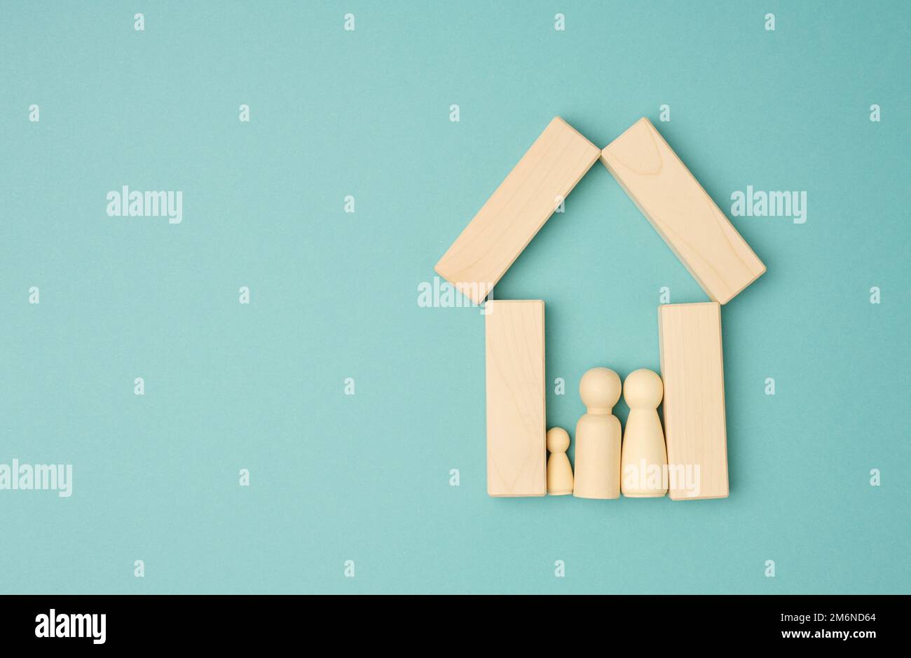 Figurines de famille en bois, maison modèle sur fond bleu. Achat immobilier Banque D'Images