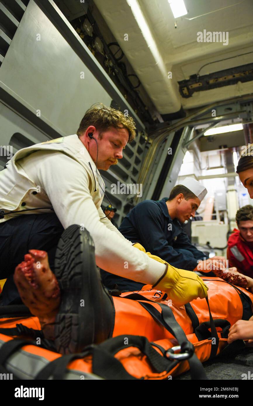 220502-N-YV347-1216 LES marins DE L'OCÉAN PACIFIQUE (2 mai 2022) sécurisent un patient simulé pour le transport lors d'une évolution de formation à la réponse médicale dans la baie hangar du destroyer à missiles guidés de classe Zumwalt USS Michael Monsoor (DDG 1001) dans le cadre d'un exercice de contrôle des dommages. Monsoor mène actuellement des opérations de routine aux États-Unis Troisième parc. Banque D'Images