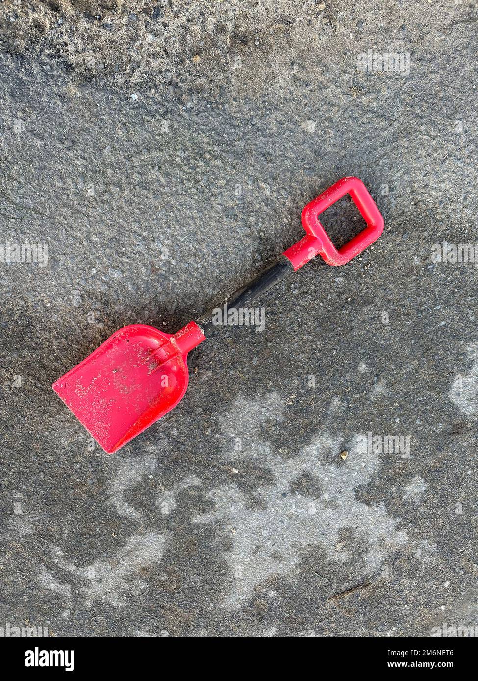 bêche rouge pour enfant sur un chemin en béton Banque D'Images