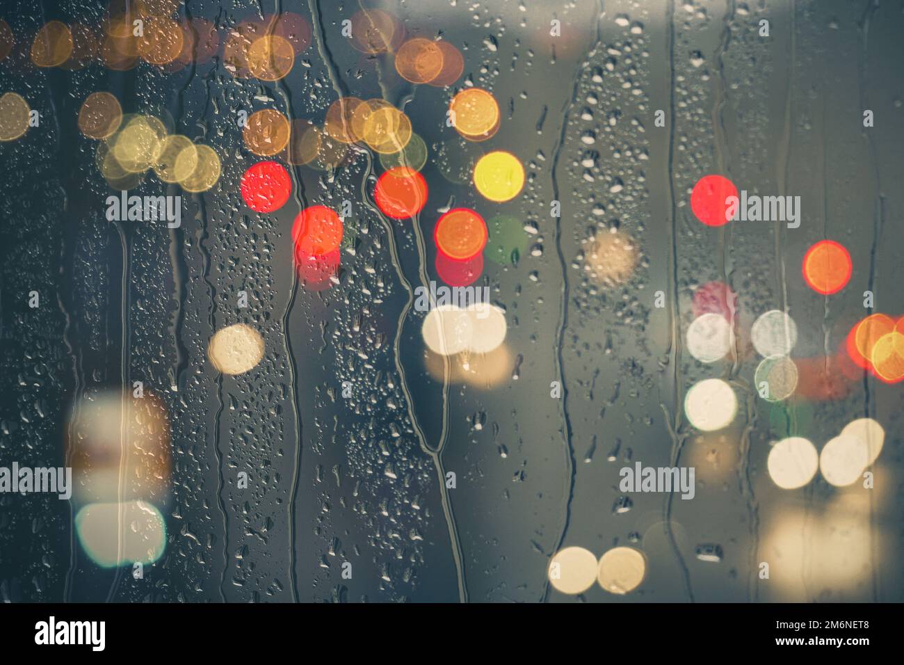 gouttes de pluie sur la fenêtre et lumières de rue arrière-plan la nuit Banque D'Images