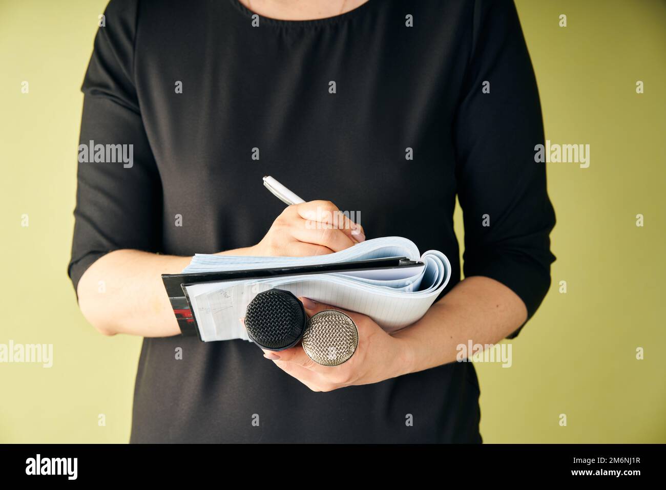 Journaliste féminine à la conférence de presse écrivant des notes et tenant un microphone Banque D'Images