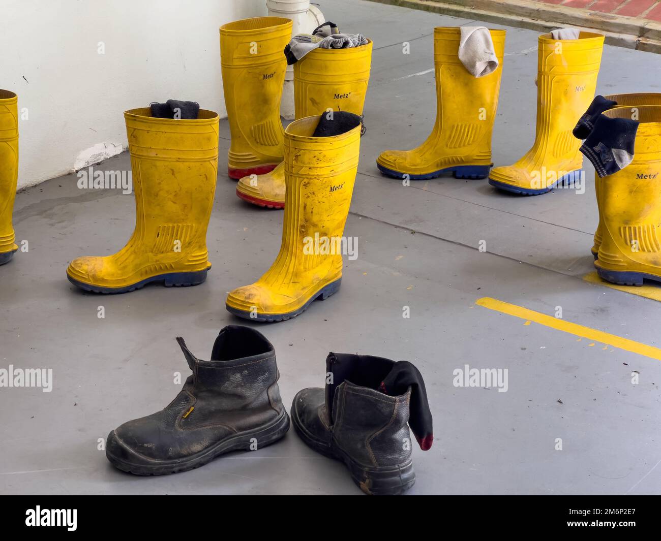 Bottes jaunes à coupe haute et chaussures de sécurité noires reposant sur le sol. Les travailleurs avaient enlevé leurs chaussures pour faire une sieste pendant leur pause. Singapour. Banque D'Images