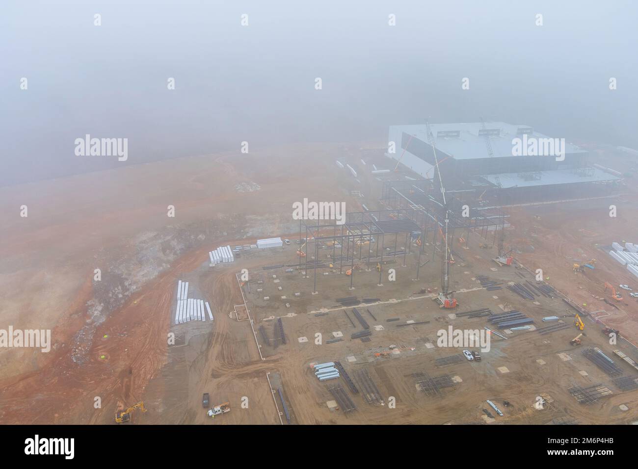 Dans le bâtiment commercial du chantier, une tour de grues travaille à l'aube pendant un brouillard épais Banque D'Images