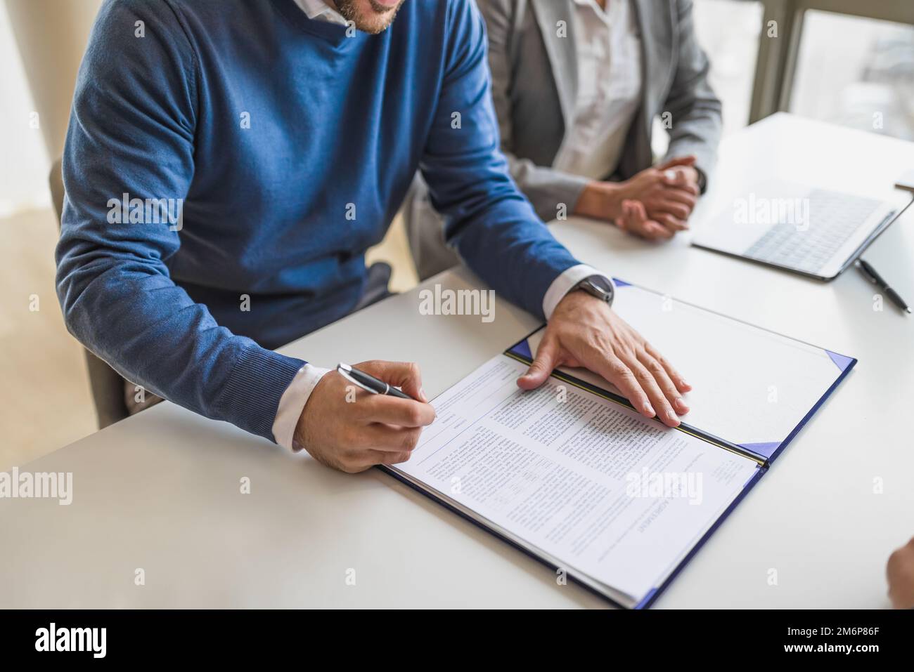 Photo d'homme d'affaires ou d'entrepreneur en chandail bleu, laissant une signature sur un document pour la finance. Banque D'Images