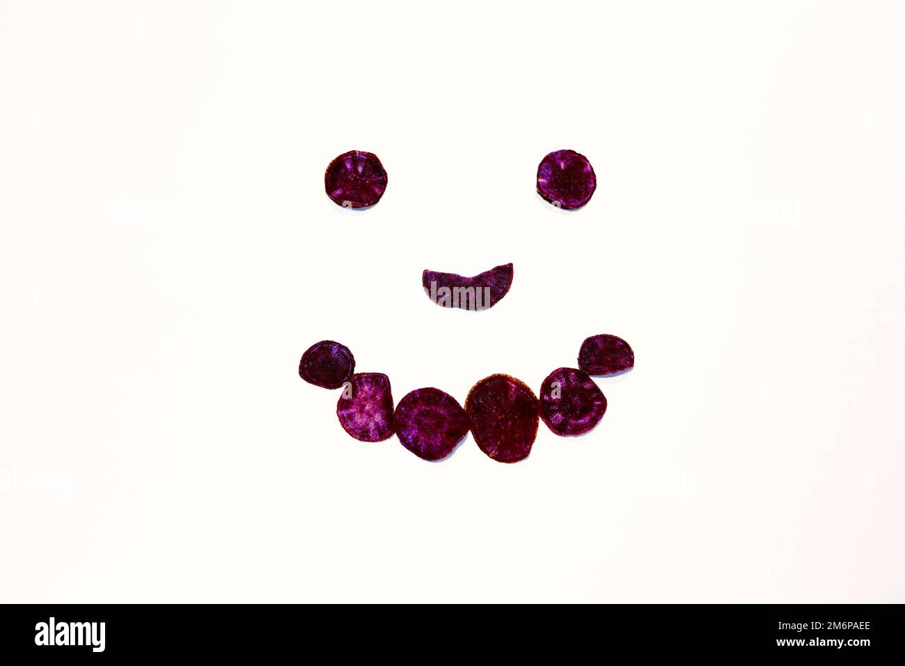 Souriez le visage avec des patates douces violets séchées sur fond blanc Banque D'Images