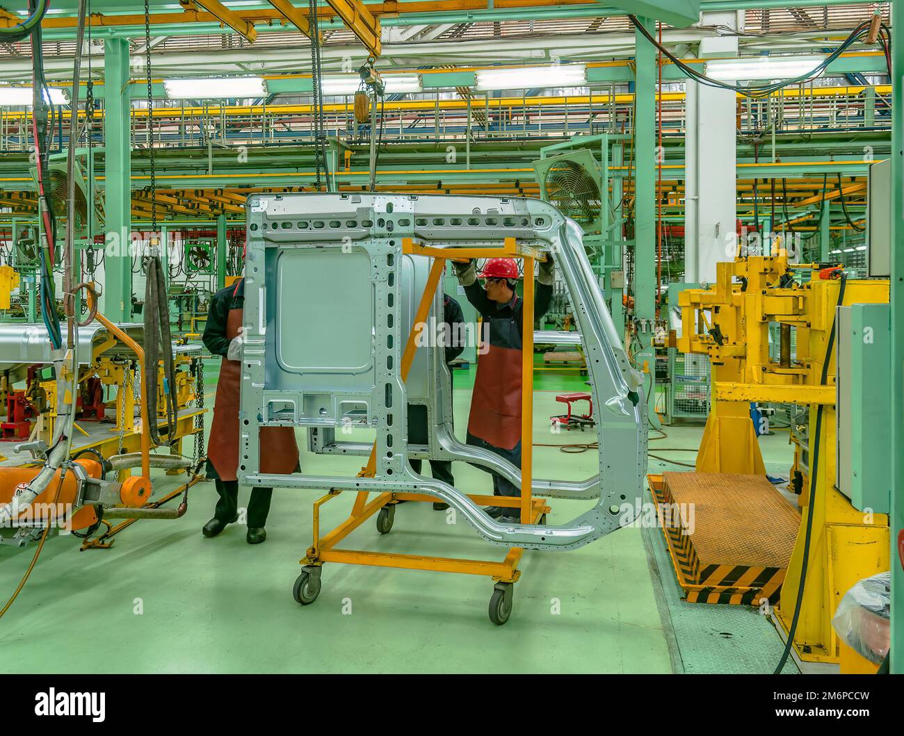 Deux travailleurs qui déplacent la cabine d'un camion dans une usine de camions en Asie. Banque D'Images