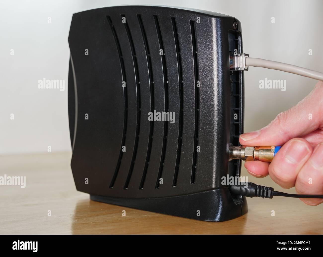 Connexion du câble coaxial au modem câble. Homme installant un accès Internet haut débit. Banque D'Images