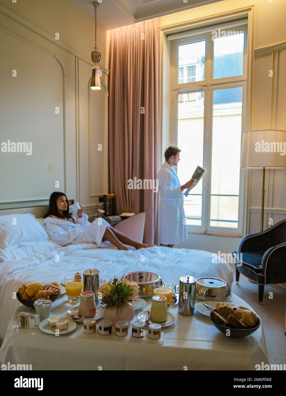 Réveil matinal au lit à Paris avec le petit déjeuner café et un journal, hommes et femmes honymoon Banque D'Images