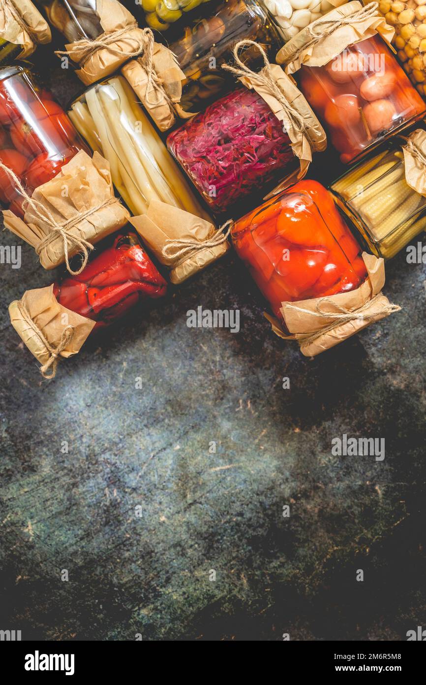 Pots de cornichons fermés avec divers légumes sur table en pierre Banque D'Images