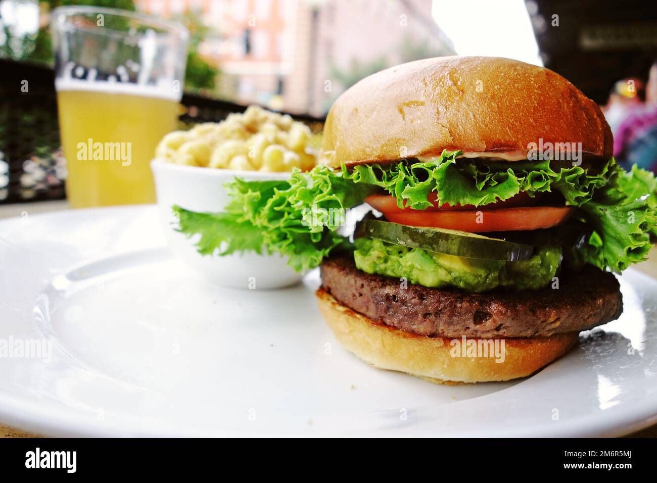Hamburger à base de plantes avec guacamole, tomate, cornichons et laitue et bière artisanale en arrière-plan Banque D'Images Hamburger à base de plantes avec guacamole, tomate, cornichons et laitue et bière artisanale en arrière-plan Banque D'Images