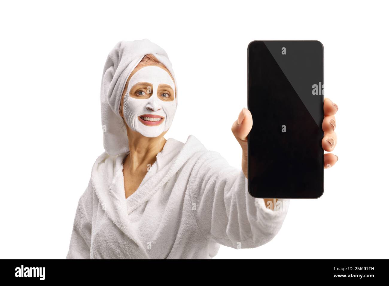 Femme dans un peignoir avec un masque facial montrant un smartphone isolé sur fond blanc Banque D'Images