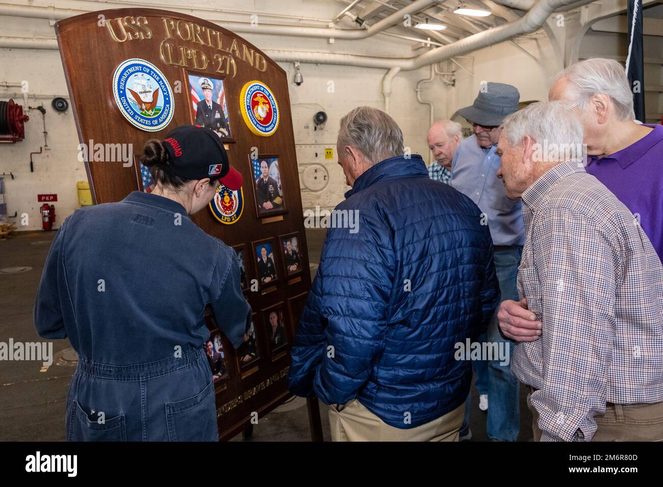 220504-N-VQ947-1094 SAN DIEGO (4 mai 2022) — Lt j.g. Dory Lustig, à gauche, le représentant des affaires publiques à bord du quai de transport amphibie USS Portland (LPD 27), présente le plateau de quai du navire aux membres retraités du quai de transport amphibie de la classe Austin désaffecté USS Ogden (LPD 5), 4 mai 2022. Portland est un quai de transport amphibie de classe San Antonio, à San Diego. Banque D'Images