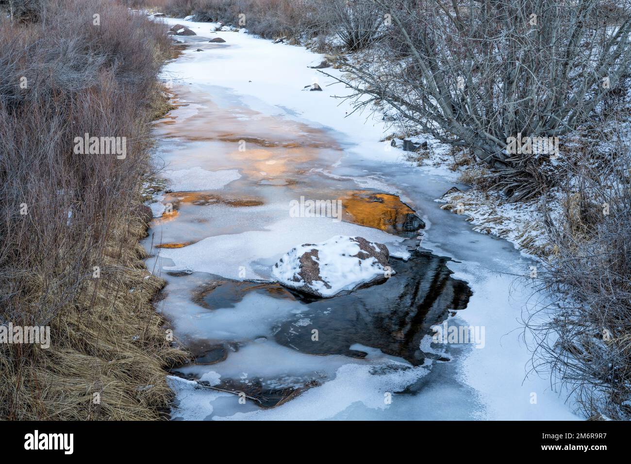 ruisseau gelé avec reflets du coucher du soleil - fourche nord de la rivière cache la poudre dans l'espace ouvert Eagle Nest dans le nord du Colorado Banque D'Images