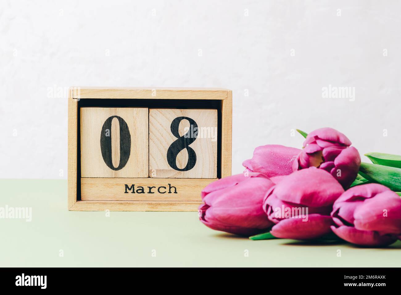 Bouquet de tulipes violettes et calendrier en bloc de bois avec date du 8 mars sur une table. Concept des fêtes de jour pour femme, gros plan. Banque D'Images