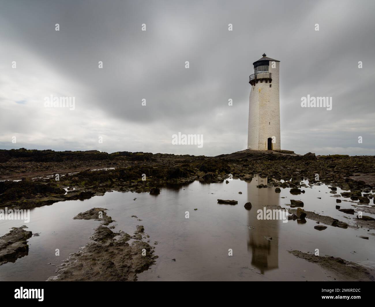 Le phare historique de la Southerness en Écosse avec des reflets dans les bassins de marée en premier plan Banque D'Images