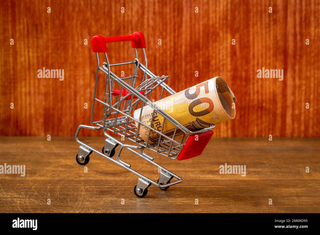 Chariot tombant avec un euro sur fond de bois Banque D'Images
