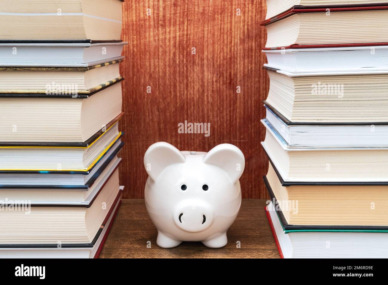 Tirelire blanche entre les livres empilés Banque D'Images