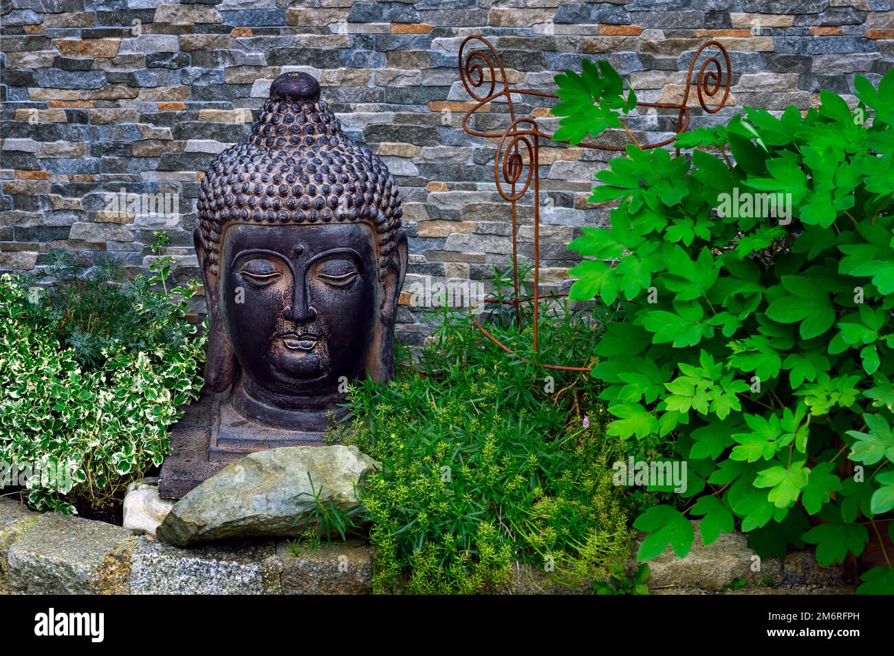 Bouddha tête devant le mur dans le jardin avant, Hindelang, Allgaeu, Bavière, Allemagne Banque D'Images