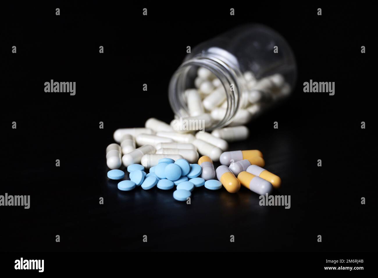 Pilules sur une table en bois noir, variation des médicaments dans les capsules dispersées d'une bouteille. Contexte pour la pharmacie, les antibiotiques, les vitamines Banque D'Images
