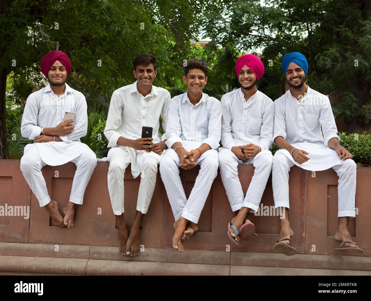 Jeunes hommes en costume blanc et pieds nus à Jallianwallala Bagh Park, Delhi, Inde Banque D'Images