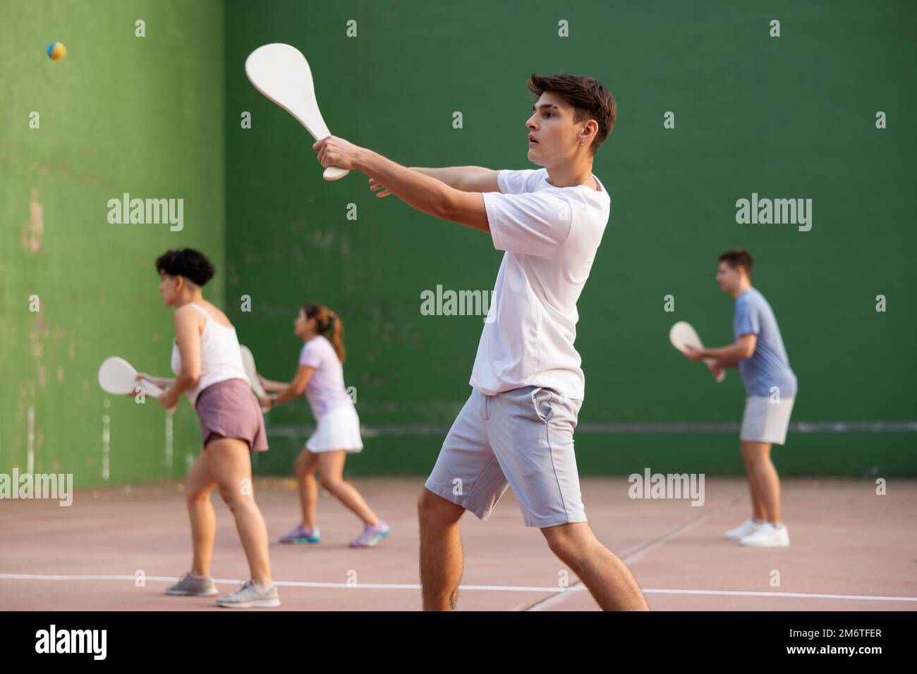Adolescent caucasien dans des vêtements de sport jouant paleta fronton sur le terrain Banque D'Images