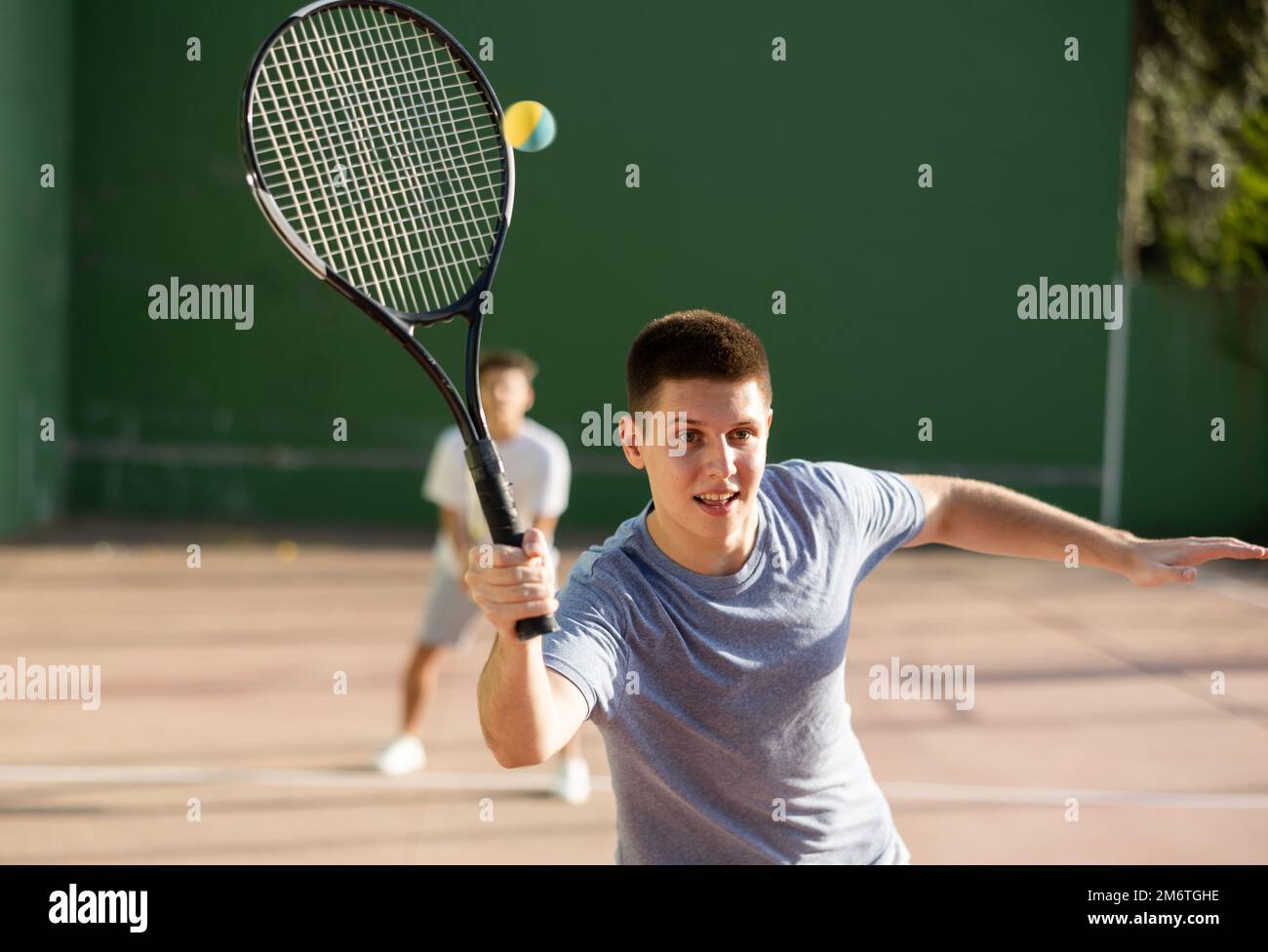 Jeune homme jouant frontenis sur un terrain de fronton en plein air en été Banque D'Images