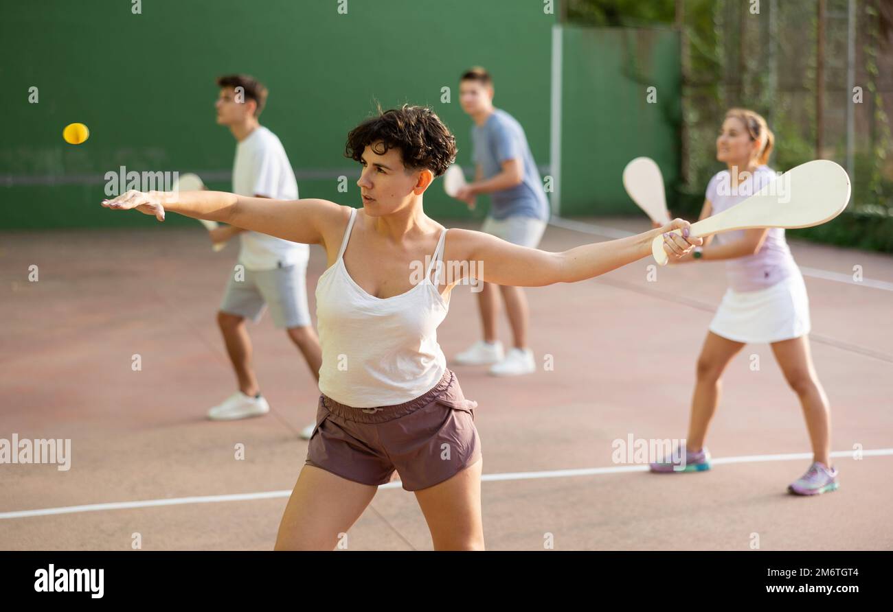 Femme servant le ballon pendant le jeu frontenis à l'extérieur Banque D'Images