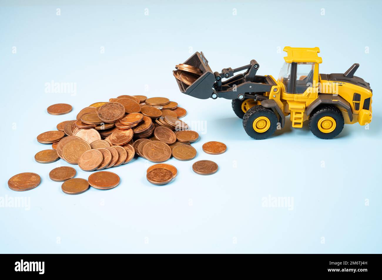 un modèle miniature d'un bulldozer déplaçant un tas de pièces de cents d'euros Banque D'Images