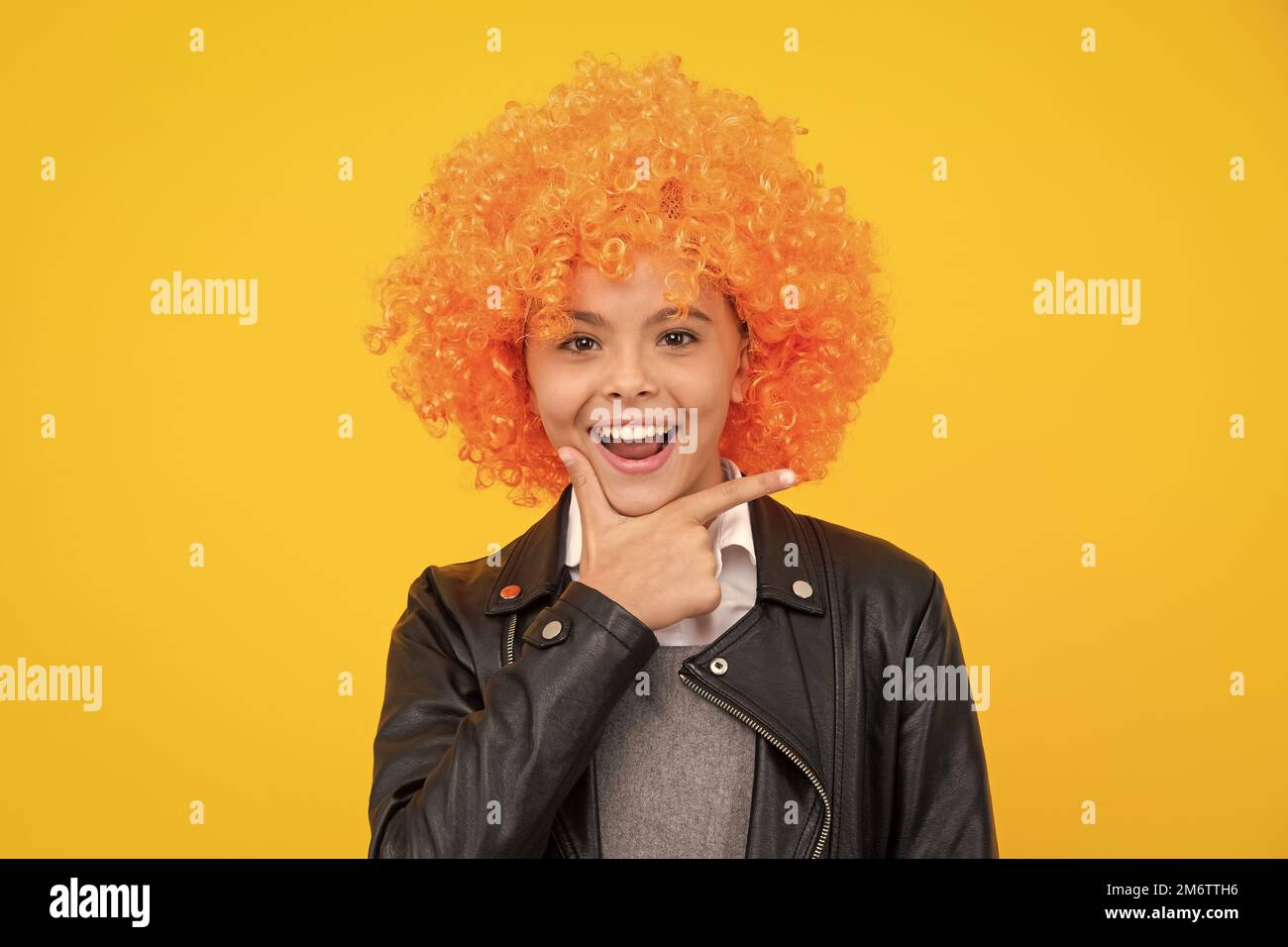 Belle adolescente dans perruque isolée sur jaune. Perruque clown amusante. Visage de fille heureux, émotions positives et souriantes. Banque D'Images