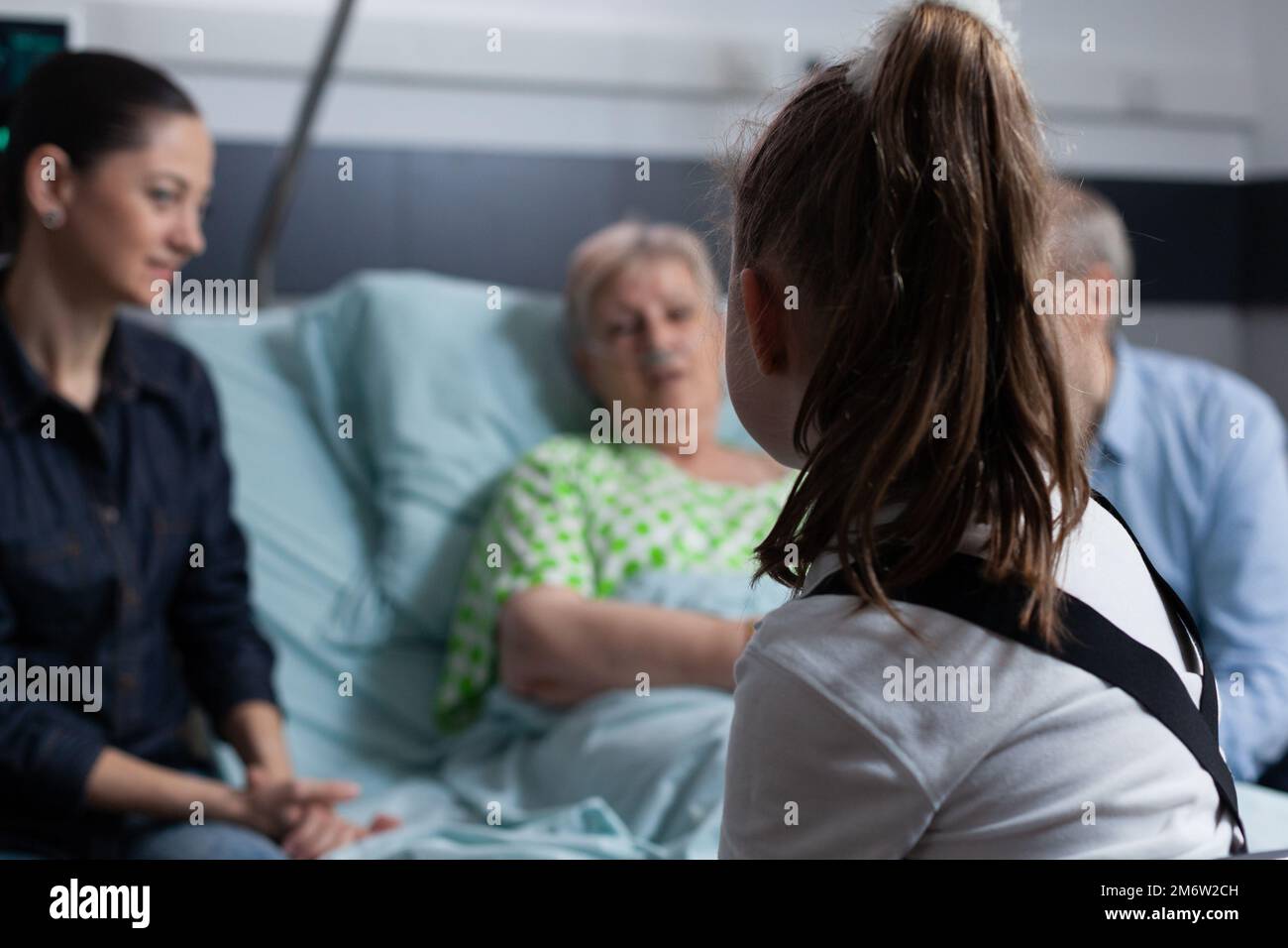 Une petite fille méconnaissable discutant avec une dame souffre de la maladie dégénérative. Enfant accompagnant la grand-mère avant l'intervention médicale par la clinique gériatrique. Banque D'Images