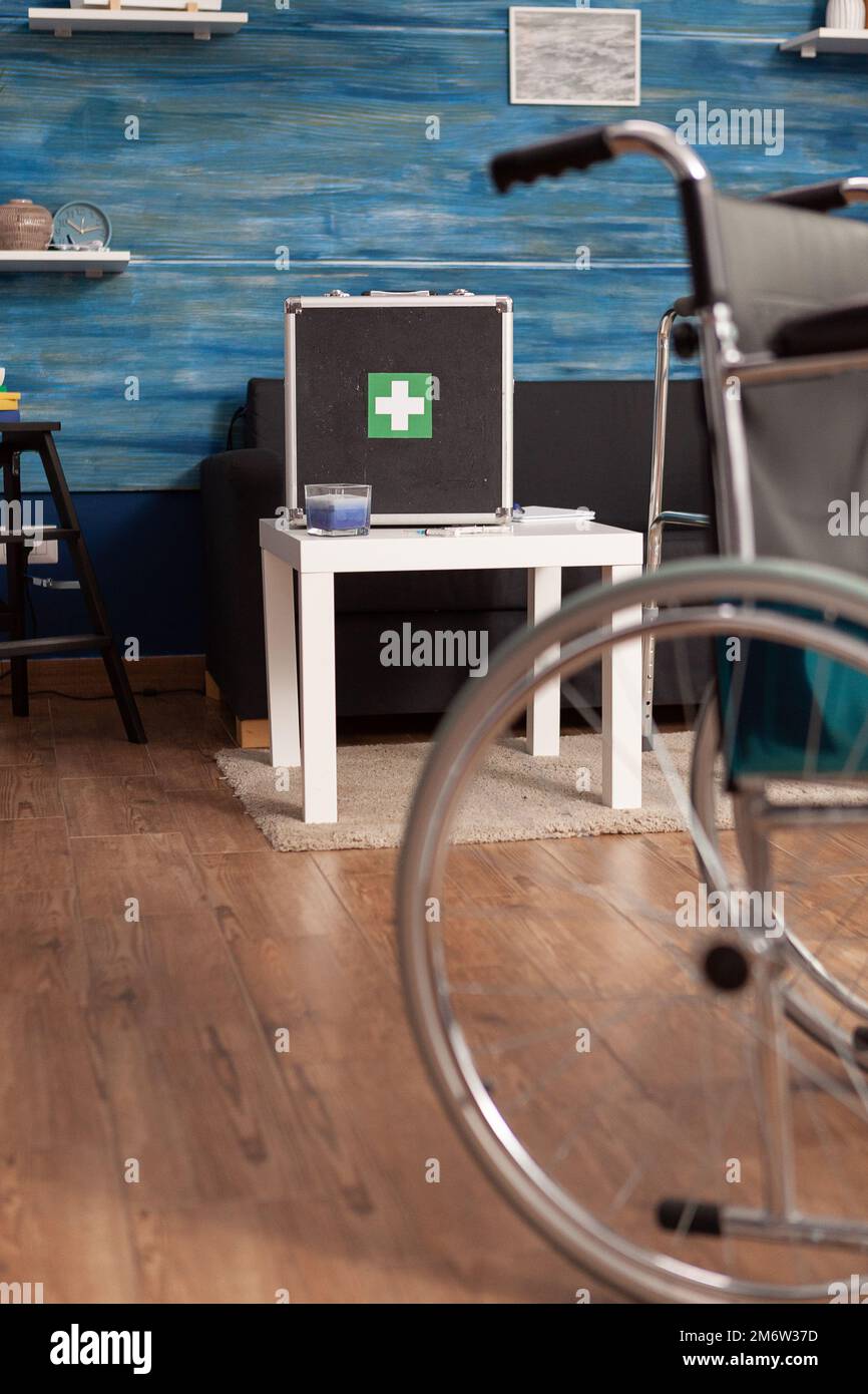 Fauteuil roulant dans une maison de soins infirmiers avec trousse de premiers soins sur la table de la salle d'attente en arrière-plan. Zone commune sans personnes, disponible pour les patients ayant besoin de séances de physiothérapie et de réadaptation. Banque D'Images
