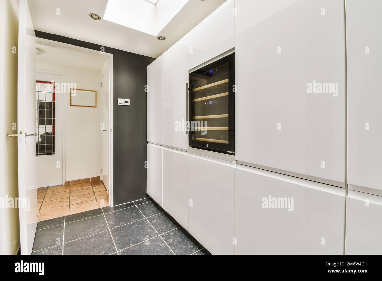 une cuisine moderne avec des armoires blanches et des comptoirs noirs sur le mur, dans un espace ouvert pour la cuisine Banque D'Images