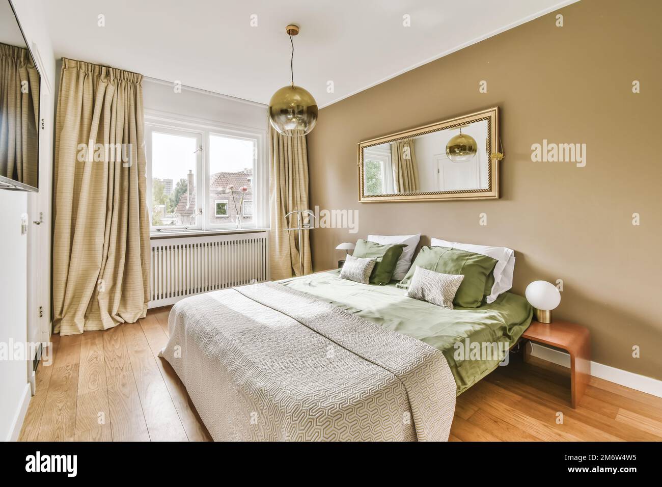 une chambre avec un lit, une commode et un miroir sur le mur en face du lit il y a un parquet Banque D'Images