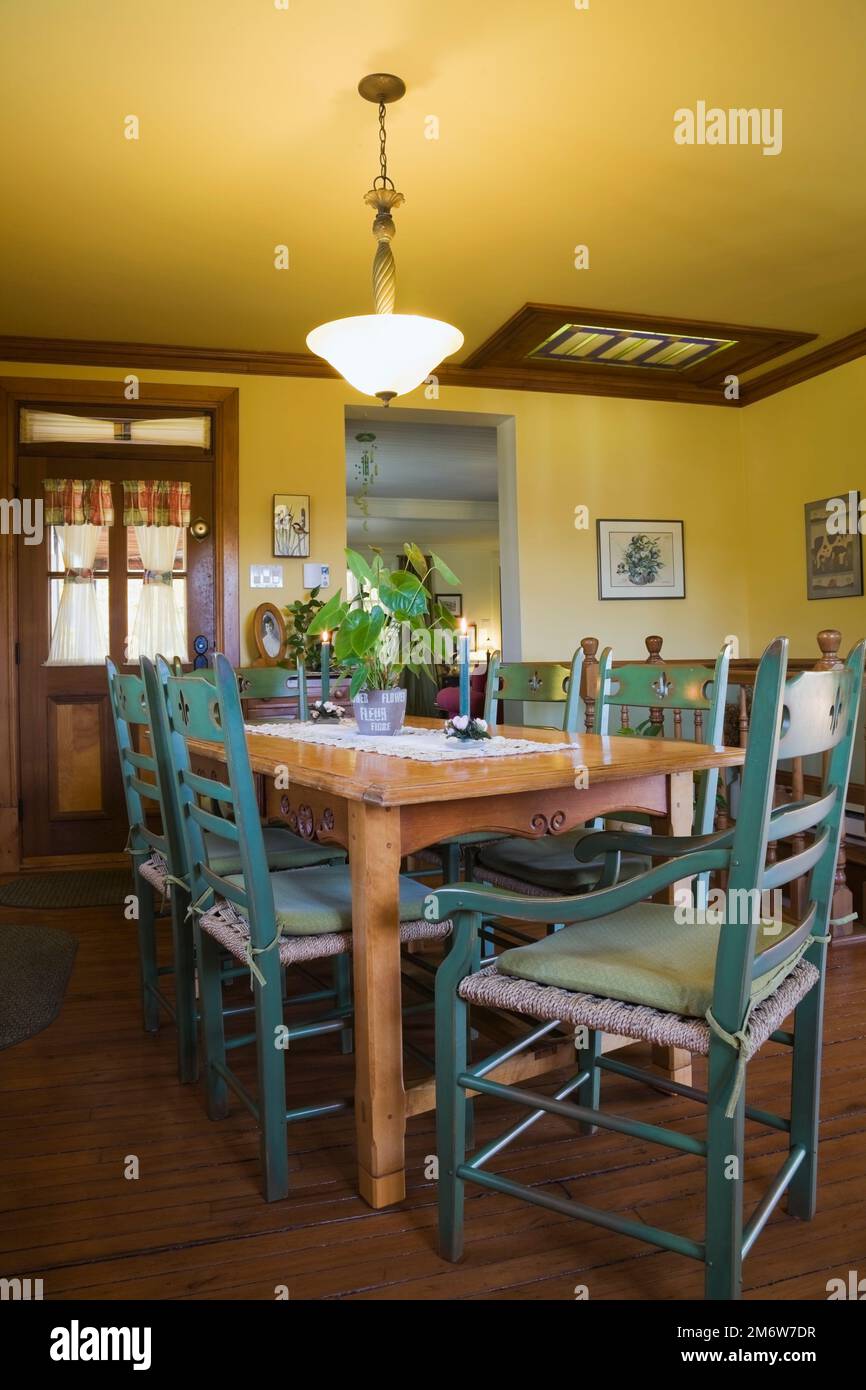 Table à manger en bois antique avec chaises à dossier haut vertes dans la cuisine à l'intérieur de la vieille maison de style cottage 1877. Banque D'Images