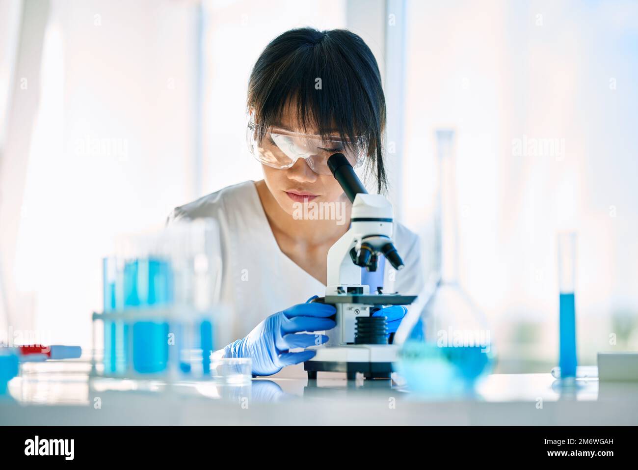Portrait d'un scientifique asiatique regardant à travers un microscope travaillant sur la recherche médicale dans un laboratoire moderne Banque D'Images