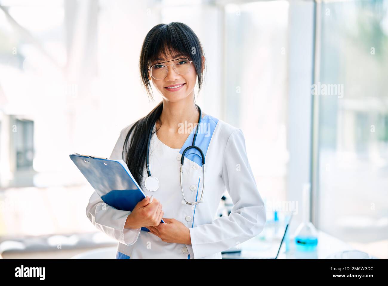 Femme souriante médecin asiatique avec stéthoscope portant dans une blouse de laboratoire regardant l'appareil photo Banque D'Images